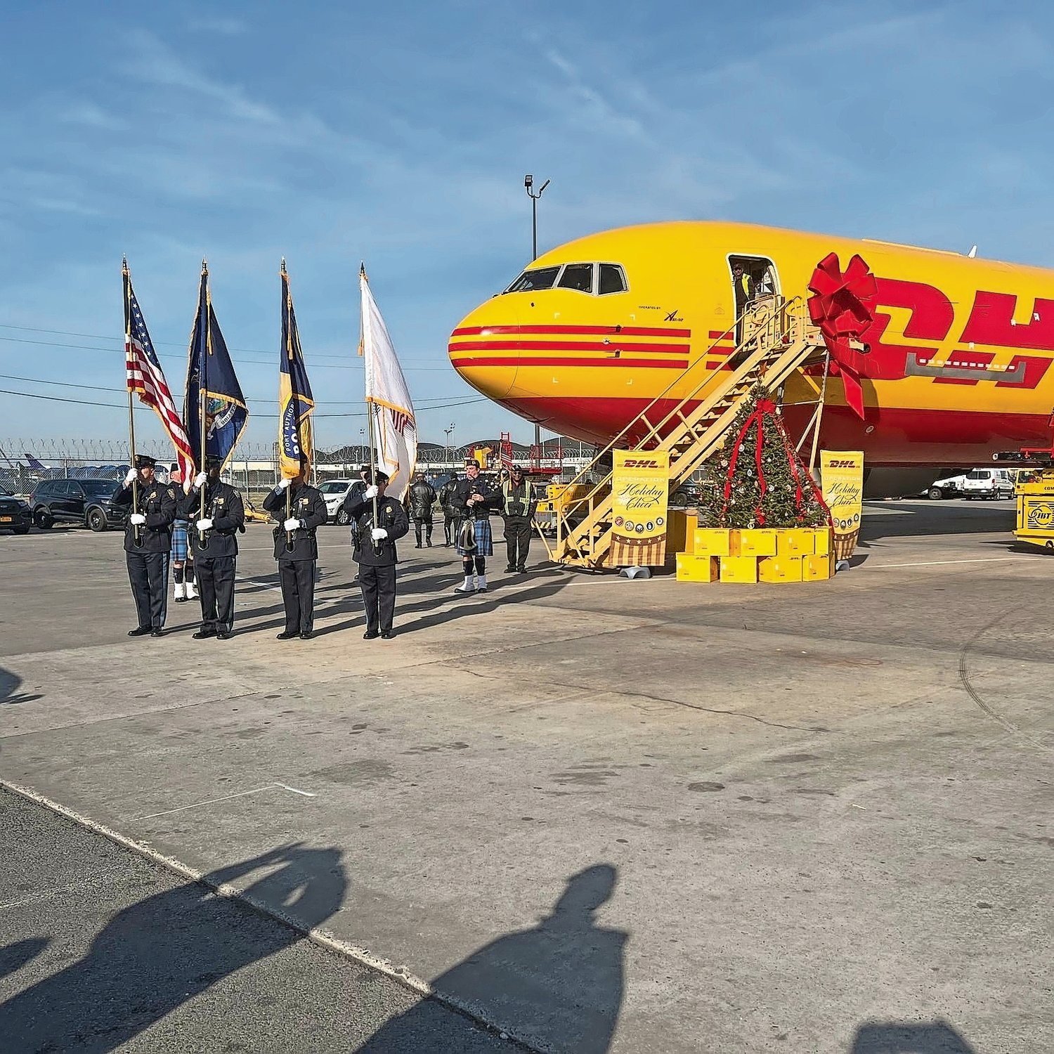 Representatives from the East Rockaway FD, the Port Authority, NYPD, and NCPD beside the DHL plane that will be going to international countries to drop off trees.
